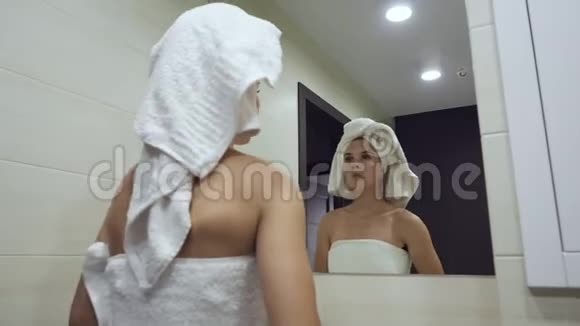 年轻女子看着镜子沐浴后摸着脸视频的预览图