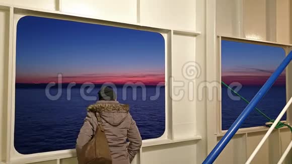 当爱尔兰渡轮在日落时分从法国的瑟堡驶往都柏林港时一位女士正透过舷窗眺望视频的预览图