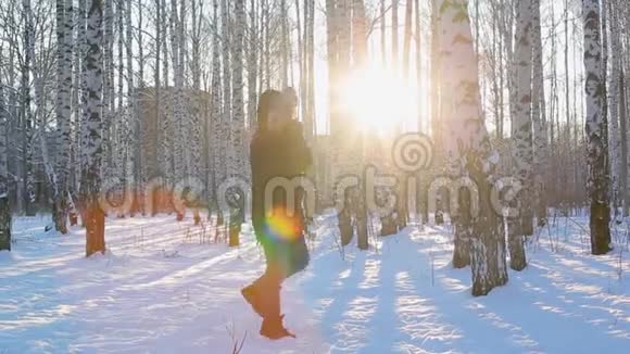穿着深色冬季夹克和带毛衣的年轻人从寒冷中跳下来并试图在带有桦树的图案城市公园保暖视频的预览图