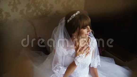 美丽的新娘摆在窗边手捧花束新娘早上视频的预览图