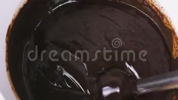 将液体黑巧克力与搅拌机混合在白色碗中特写双手视频的预览图