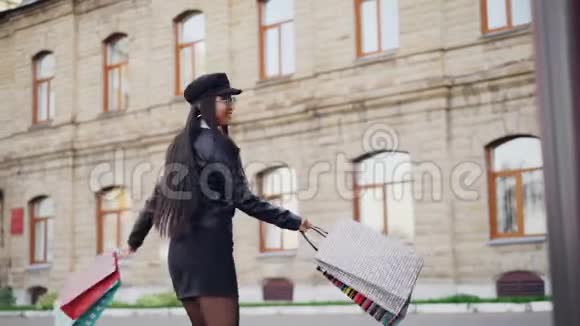 慢动作肖像快乐的亚洲女人在街上旋转拿着礼品袋后一天的购物积极正面视频的预览图