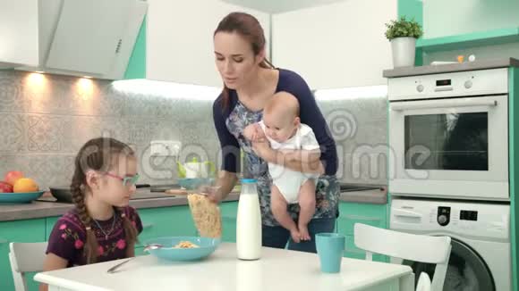 女孩和妈妈和男孩一起吃麦片早餐家庭早餐时间视频的预览图
