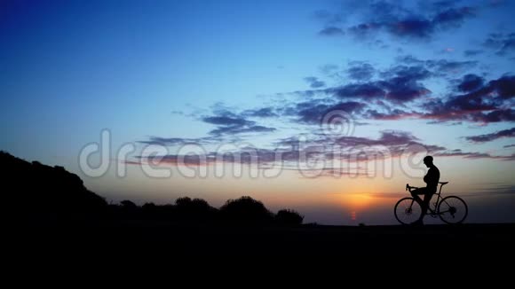那个人站在日落的背景下骑着自行车时间流逝捕捉宽角度视频的预览图