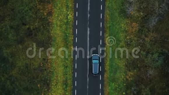 无人机顶视图摄像机跟踪黑色汽车行驶在空高速公路上沿着多云的秋林进行大气道路旅行视频的预览图