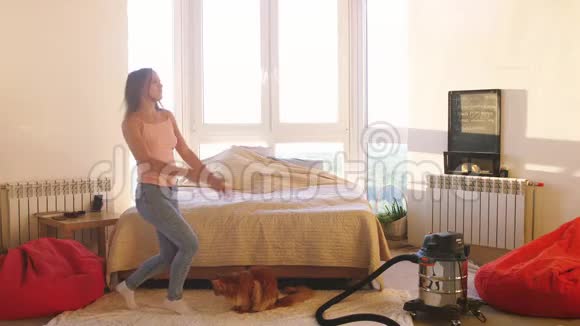 快乐无忧无虑的年轻黑发女人在卧室和大窗户跳舞听音乐在家里玩缅因州视频的预览图