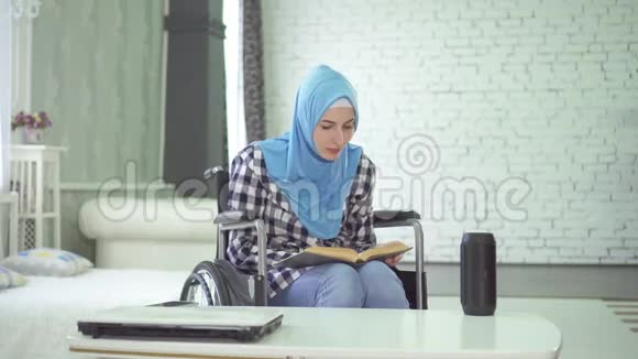 戴头巾轮椅残疾的漂亮年轻女子用声音作为学习和教育的助手视频的预览图