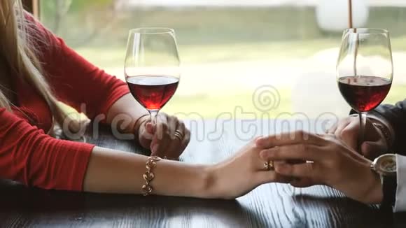 在浪漫的晚餐中亲密的情侣牵着手碰着酒杯视频的预览图