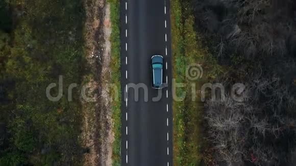 俯视无人机跟随黑色SUV汽车在多云秋林公路上行驶冒险概念视频的预览图