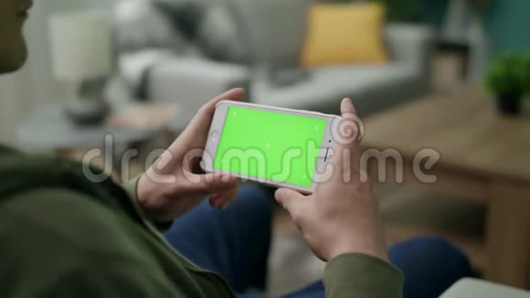 一个男人在客厅的绿色屏幕上看视频视频的预览图