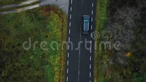 景区高空俯视特写无人机跟踪黑色SUV车沿公路公路行驶沿多云秋林视频的预览图