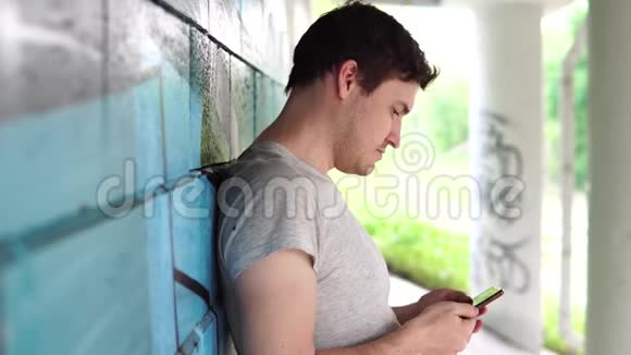 一个穿着日常服装的人的街道肖像那个人用电话一个人在智能手机上拨信息视频的预览图