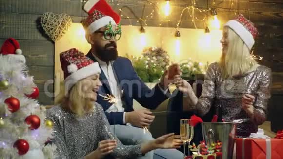 在家里举行新年聚会男人和两个女孩庆祝圣诞节喝香槟和燃烧的火花灯概念视频的预览图