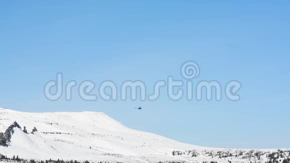 阳光明媚的一天一架救援直升机飞过覆盖着积雪的山脉视频的预览图