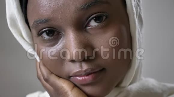戴头巾的年轻悲伤的非洲穆斯林女孩正在镜头前观看宗教概念灰色背景视频的预览图
