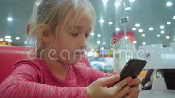 女孩子在咖啡馆的桌子上拿着电话集中年轻的女青少年坐在咖啡馆里在视频的预览图