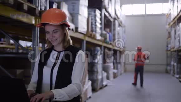 女仓库工人戴着安全帽用笔记本电脑做笔记视频的预览图