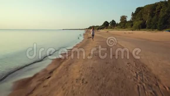 日落时在沙滩上奔跑的女人视频的预览图