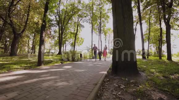 幸福的年轻一家沿着小巷在公园里散步视频的预览图