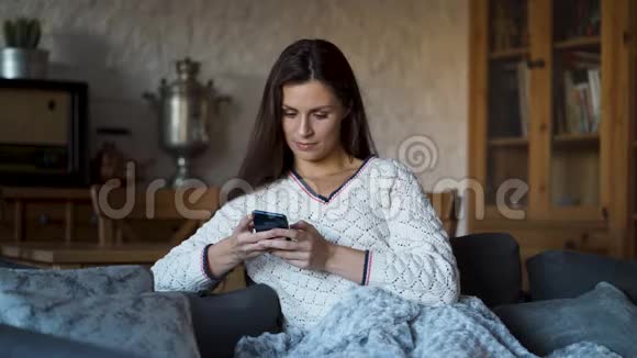 女人坐在沙发上裹着毯子在电话里发短信视频的预览图