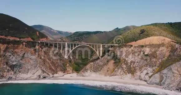 无人机飞往标志性的比克斯比溪桥在1号高速公路在大苏尔美国惊人的电影天桥背景拍摄视频的预览图