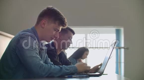 一大群多民族学生在笔记本电脑上工作同时在现代课堂上听讲座明亮明亮视频的预览图
