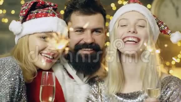 靠近一个长胡子的男人和两个金发女孩燃烧孟加拉灯新年派对新年的心情圣诞节视频的预览图