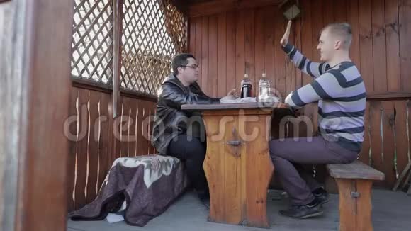 两个人坐在桌子旁从塑料瓶里喝啤酒快乐视频的预览图