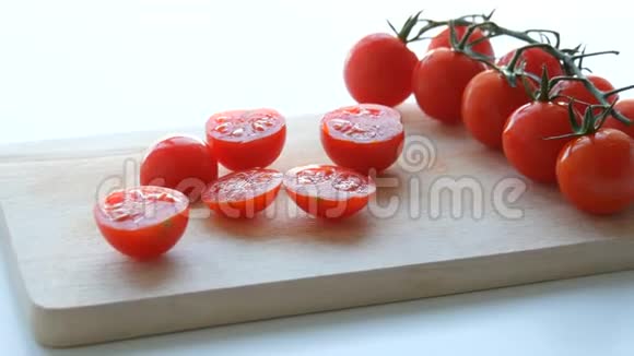美丽多汁成熟的切好的红樱桃西红柿成簇白色桌子背景和木制厨房板视频的预览图