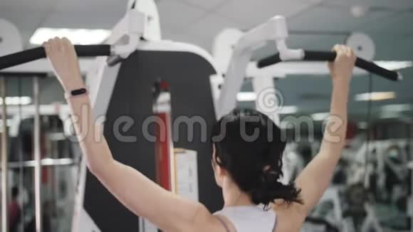 体育俱乐部的健身教练在模拟器上做拉力以加强肩部肌肉一个女人做视频的预览图