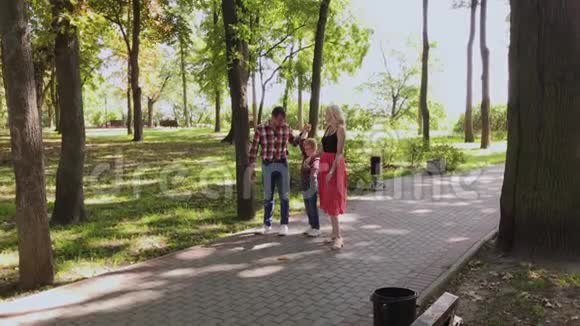 幸福的年轻一家沿着小巷在公园里散步视频的预览图