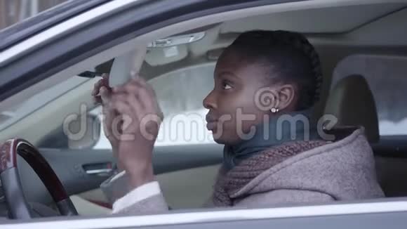 自信的非洲裔美国妇女坐在车里嚼口香糖的特写美丽的女人开车视频的预览图