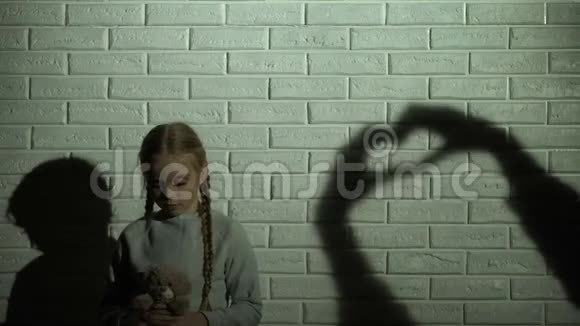 女孩看着墙上的心影拥抱着泰迪熊希望和善良视频的预览图