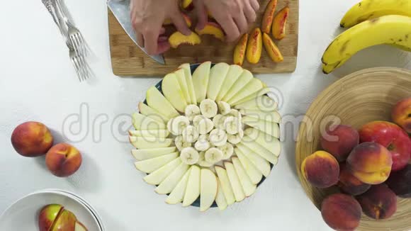 苹果香蕉和桃子片在盘子里妇女安排水果拼盘视频的预览图