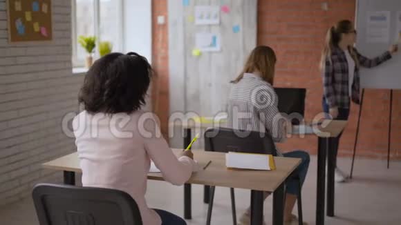 学生在讲座上问老师一个问题女孩坐在桌子旁举手老师视频的预览图