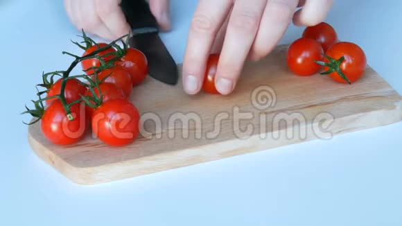 女人的手在白色的桌子背景和木制的厨房板上的树枝上切着美丽多汁成熟的红樱视频的预览图