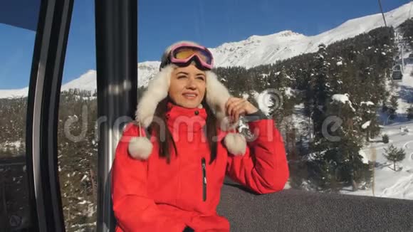 穿着滑雪服和滑雪护目镜的女孩坐在缆车上的缆车上滑雪场视频的预览图