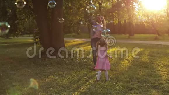 一群快乐的小女孩在玩试图抓住大空气肥皂泡泡鼓视频的预览图