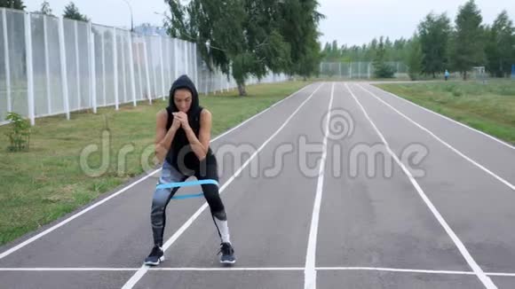 可爱的运动女孩做腿部运动与健身橡皮筋户外视频的预览图