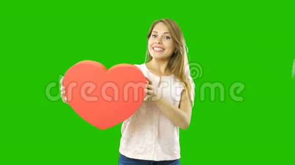 年轻漂亮的女人拿着一个心形的盒子从一边到另一边微笑着新年节日和礼物视频的预览图