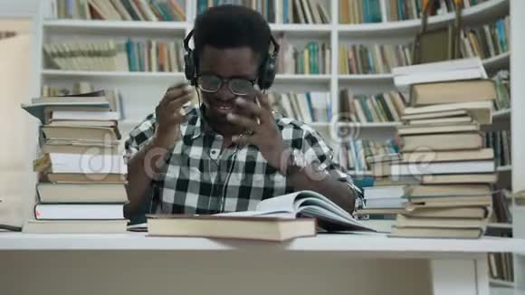 压力大的非洲年轻人在耳机里学习开始在时尚的图书馆尖叫视频的预览图