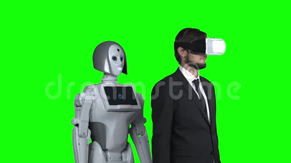 戴着虚拟现实眼镜的人拿起机器人在后面重复绿色屏幕视频的预览图