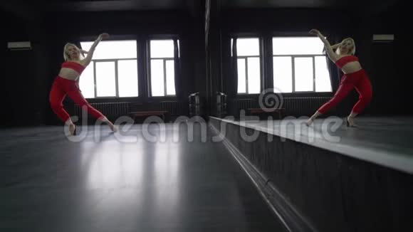 性感的金发女孩在镜子附近的工作室里跳舞视频的预览图