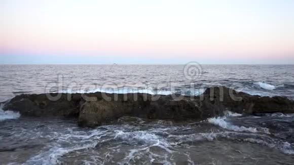 波在地中海上波浪在粉红色日落时撞击岩石慢动作视频的预览图