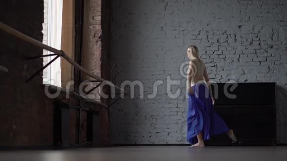 穿蓝色裙子的金发舞者在一条腿上缓慢地分裂视频的预览图