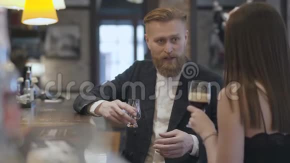 坐在酒吧柜台前的可爱的黑发女人和金发胡须男关门了夜间生活方式的概念可爱的一对视频的预览图