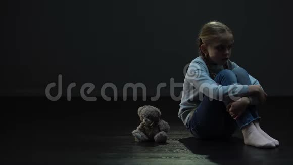 小女孩独自坐在黑暗的房间里抱着泰迪熊缺乏朋友视频的预览图