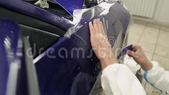 近距离拍摄的男子的手在服务站粘贴乙烯基在蓝色汽车视频的预览图