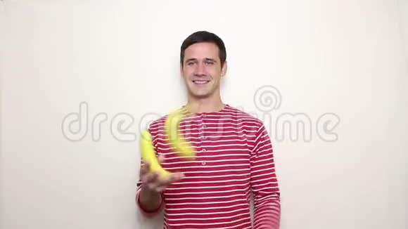 年轻的帅哥穿着一件条纹毛衣笑容满面穿着三根成熟的香蕉视频的预览图