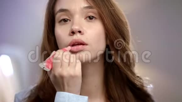 年轻女人在嘴唇上涂液体口红有唇膏光泽的美女视频的预览图